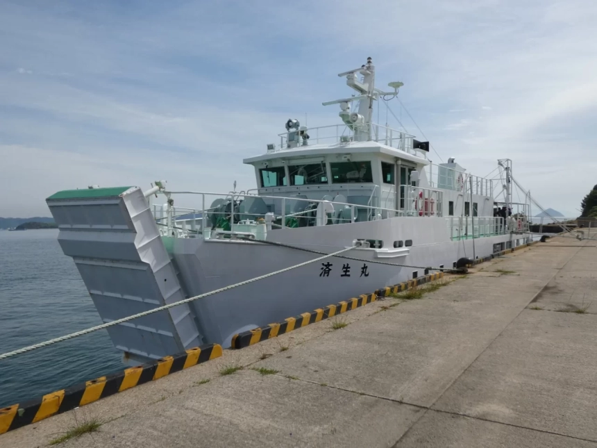 青い空と海を背景に、白い船がコンクリート製の桟橋に停泊している様子を写した一枚。船体には「済生丸」という文字が見える。